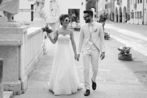 Sposi che camminano mano nella mano nel centro storico dopo il matrimonio, fotografia di matrimonio spontanea e autentica